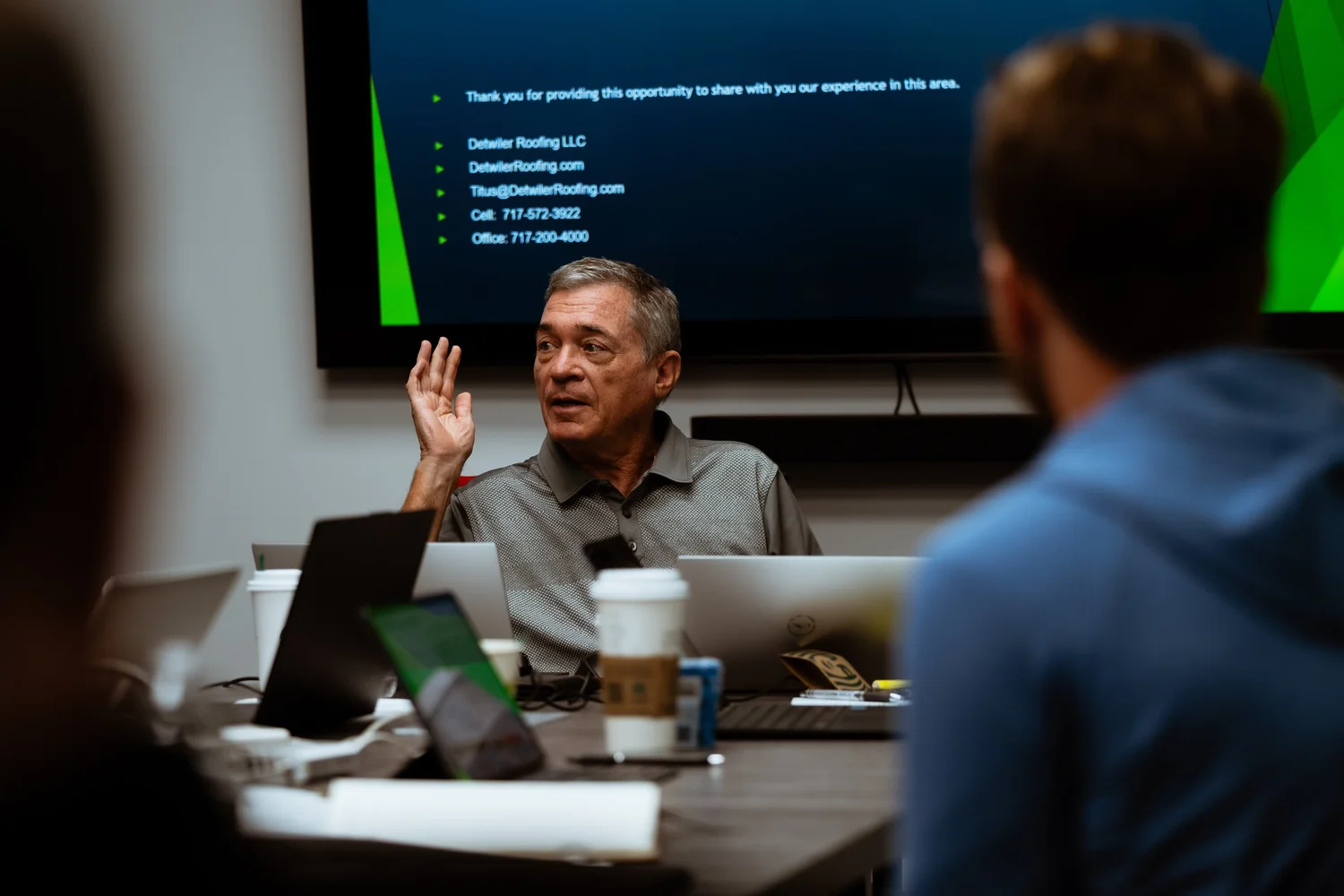 Greg Hayne speaking with roofing business owners around a meeting table